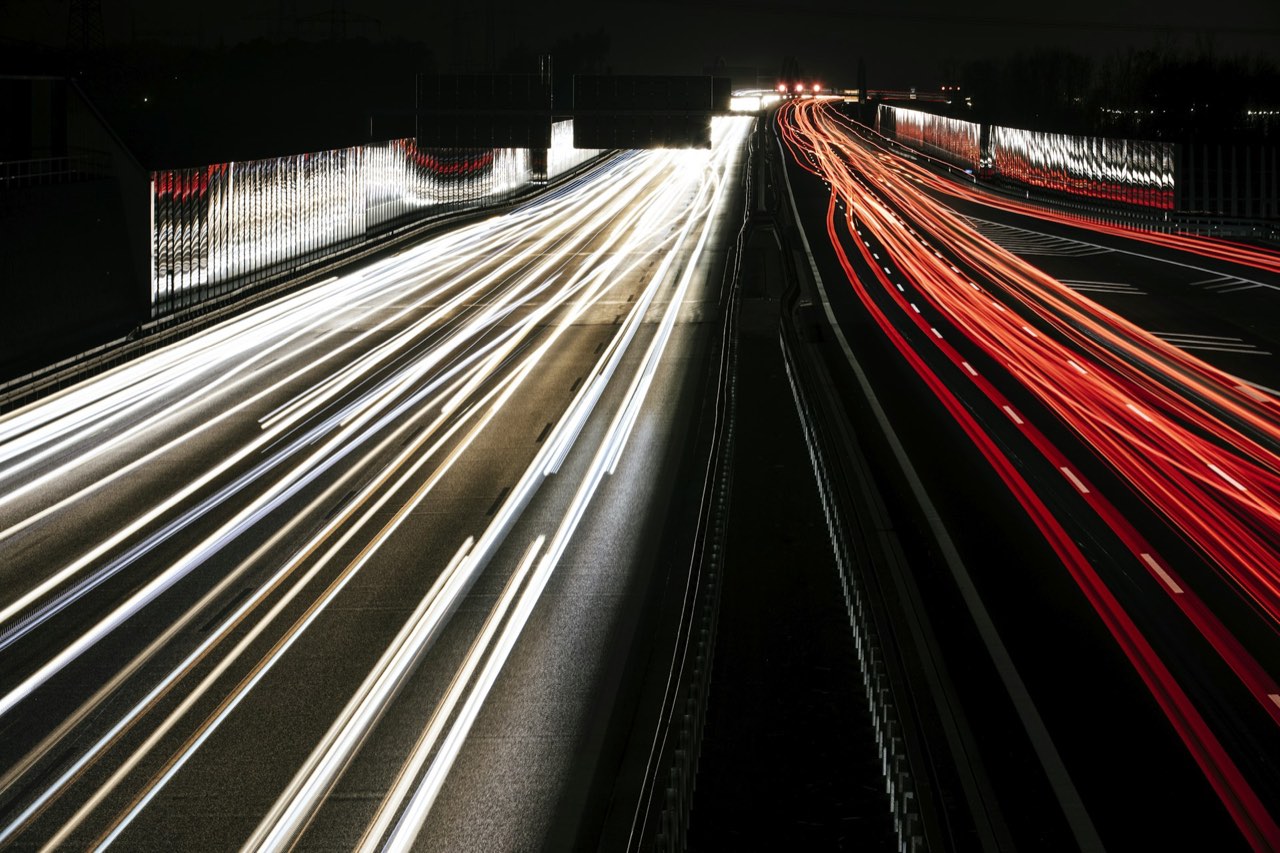 Autobahn bei Nacht mit Lichtspuren fahrender Fahrzeuge